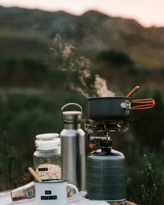 pexels photo 4909070 4909070 1 A picturesque outdoor camping scene with cooking gear and steam rising from a pot at sunrise.